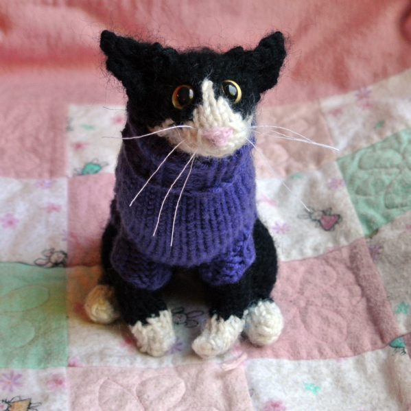 knitted black and white cat in a purple sweater